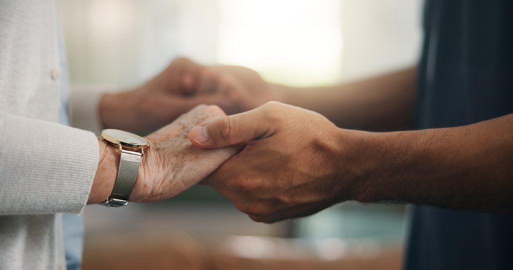 Caregiver holding hands with senior client